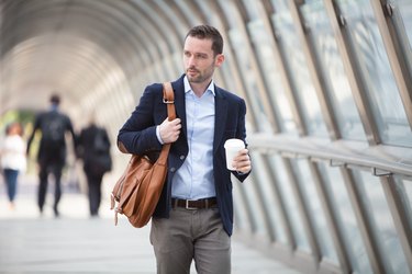 Young attractive man with stomach ulcer drinking coffee on his way