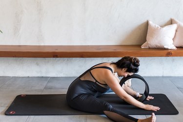 woman doing Wide-Angle Seated Forward Bend (Upavishtha Konasana) with a yoga wheel