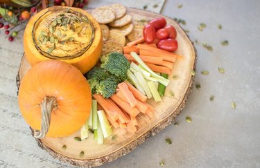 Pumpkin hummus topped with pepitas, served in a pumpkin with vegetables and crackers for dipping