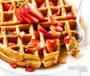 Low-carb Belgian waffle topped with sliced strawberries and syrup.