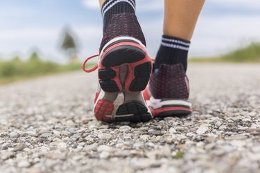 Feet of sportive woman on country lane in summer