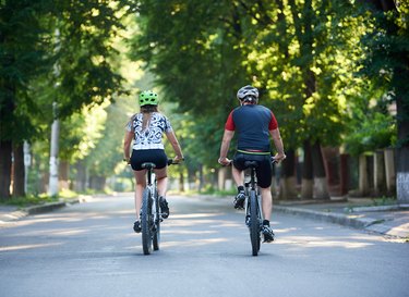 Young sporty couple riding bicycles in park.