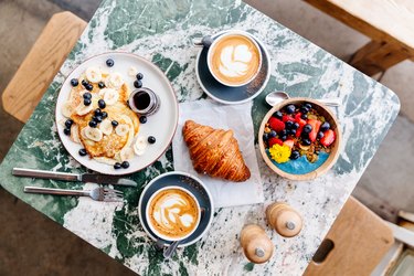 Brunch at the cafe with smoothie bowl, ricotta pancakes, croissant and cappuccino, directly above view