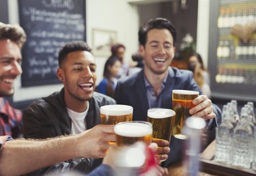 Men friends toasting beer glasses at bar