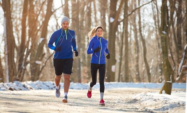 Couple in winter workout gear running together outdoors