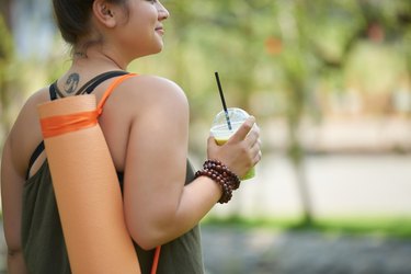 A woman drinking a smoothie after doing yoga for weight loss