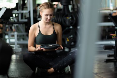 Fit beautiful young woman caucasian doing exercise at indoor workout in gym. Young woman holding dumbbell during an exercise class in a gym. Freedom happy and relax lifestyle healthcare concept.