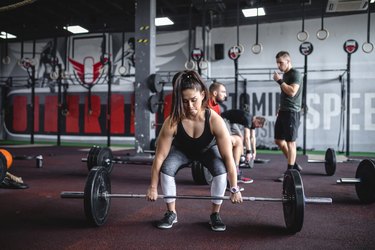 Strong female weightlifter preparing to do a deadlift