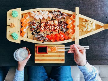 Man eating sushi from a sushi boat in Japanese restaurant, directly above personal perspective view