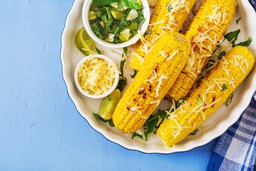 Delicious grilled  corn with basil-garlic sauce and lime. Tasty food. Top view. Flat lay