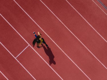 Female runner listening to music and running on sports track