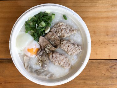 Traditional Thai porridge rice gruel in white bowl congee with many topping