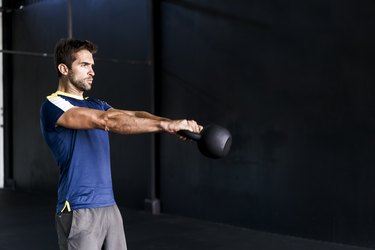 Determined male exercising in gym with kettle bell