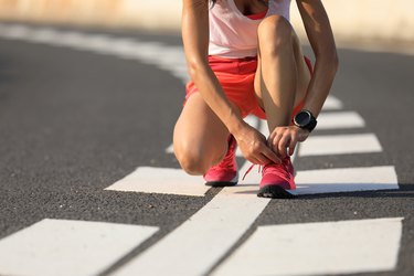 Healthy lifestyle fitness woman runner tying shoelace