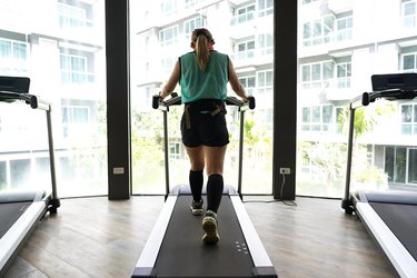 Asian woman walking on treadmill with building in background