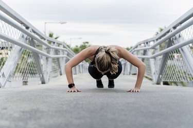 Sporty woman doing push ups, working out on a bridge