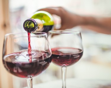 Hand pouring red wine in glasses