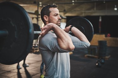 Man pulling up large barbell in fitness class