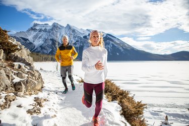 Two people exercising for cross-country running in winter jogging on snowy path