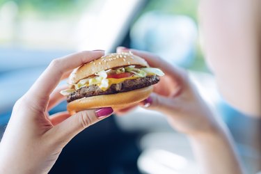 Girl thinking about whether there are antibiotics in meat of her fast-food hamburger