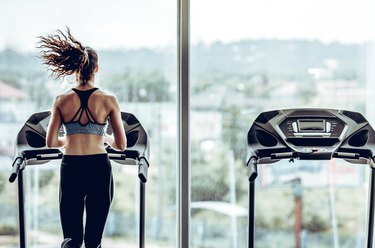 Attractive woman running on treadmill in sport gym.