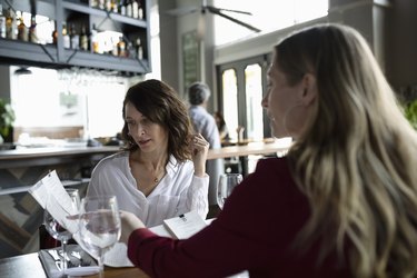 Women friends looking at a menu, dining in restaurant