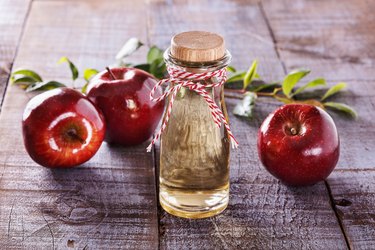 Apple cider vinegar over rustic wooden background