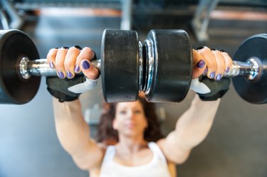 Young woman at gym working her arms with dumbbells