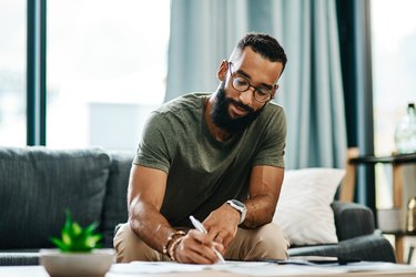 man sitting on a couch writing in a journal