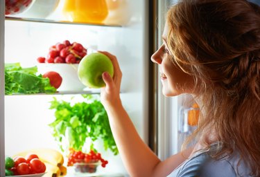 Woman peering in fridge wondering how to store vegetables