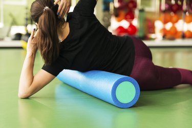 athlete doing foam roller exercise for lats on a green floor