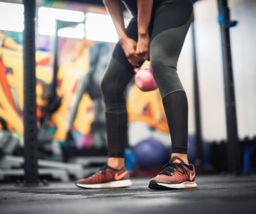 低的年轻女子举重Kettlebell在健身房