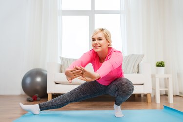 happy woman stretching leg on mat at home