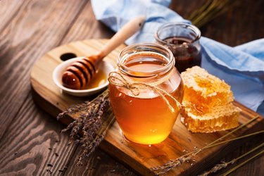 Honey in jar and bunch of dry lavender