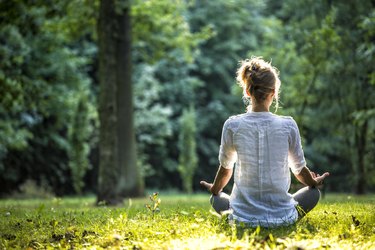 A woman meditating outdoors to help her immune system