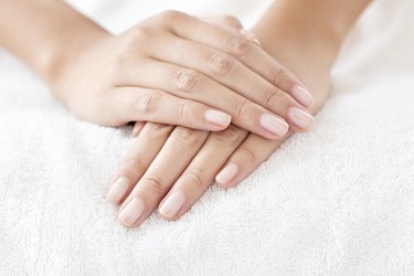 Woman with hands and nails resting on white towel