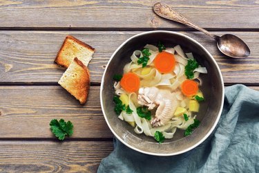 Homemade chicken noodle soup on a wooden rustic plank table. Top view, copy space.