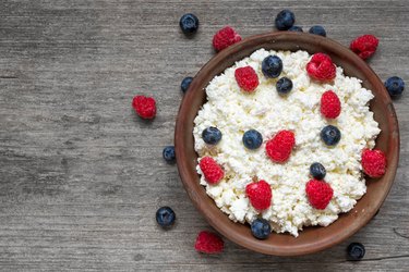 Cottage cheese with fresh raspberries and blueberries in a bowl for healthy breakfast