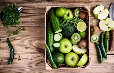 Fresh sliced green vegetables and fruits in wooden crate