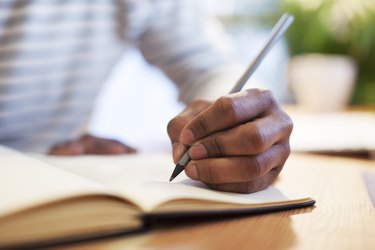 Man's hand drawing in a notebook