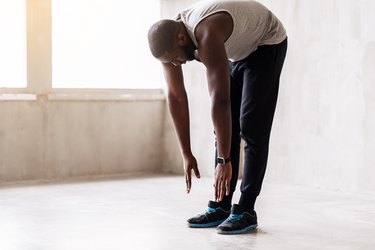 Calm muscular guy doing the inchworm exercise as part of his workout warm-up