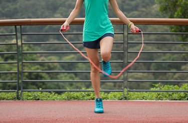 Woman athlete jumping rope on spring forest trail. woman fitness workout wellness concept.