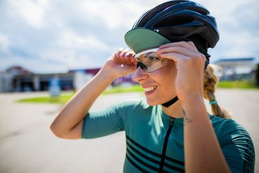 woman cyclist adjusting her bike helmet and goggles outside
