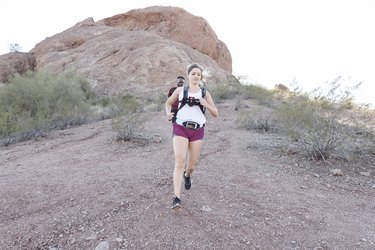 Man and woman cross country running down a mountain trail