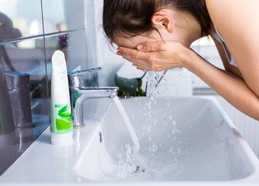 A woman washing her face in the sink