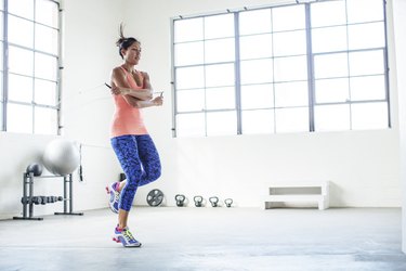 Female athlete exercising with jumping rope in gym