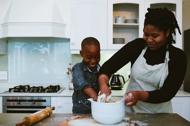 Mother and son mix dough for bread