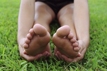 Young woman stretching, touching bottom of feet, close-up