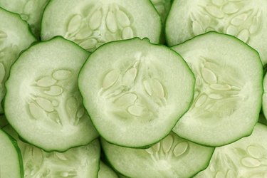 Two fresh green mini cucumbers and sliced half with three slices