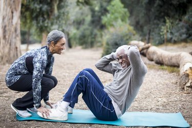 couple performing sit-ups together outside